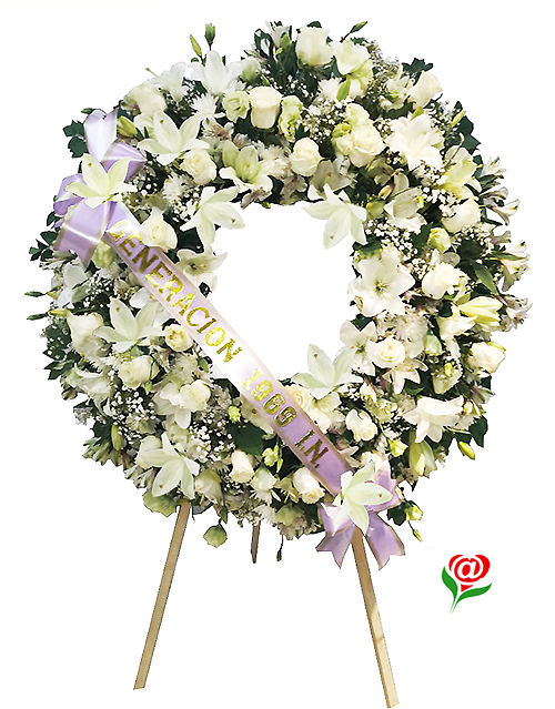 Flores para funeral formando una corona de flores blancas en que se ha dispuesto una cinta con el nombre de la persona o empresa que envía la ofrenda  